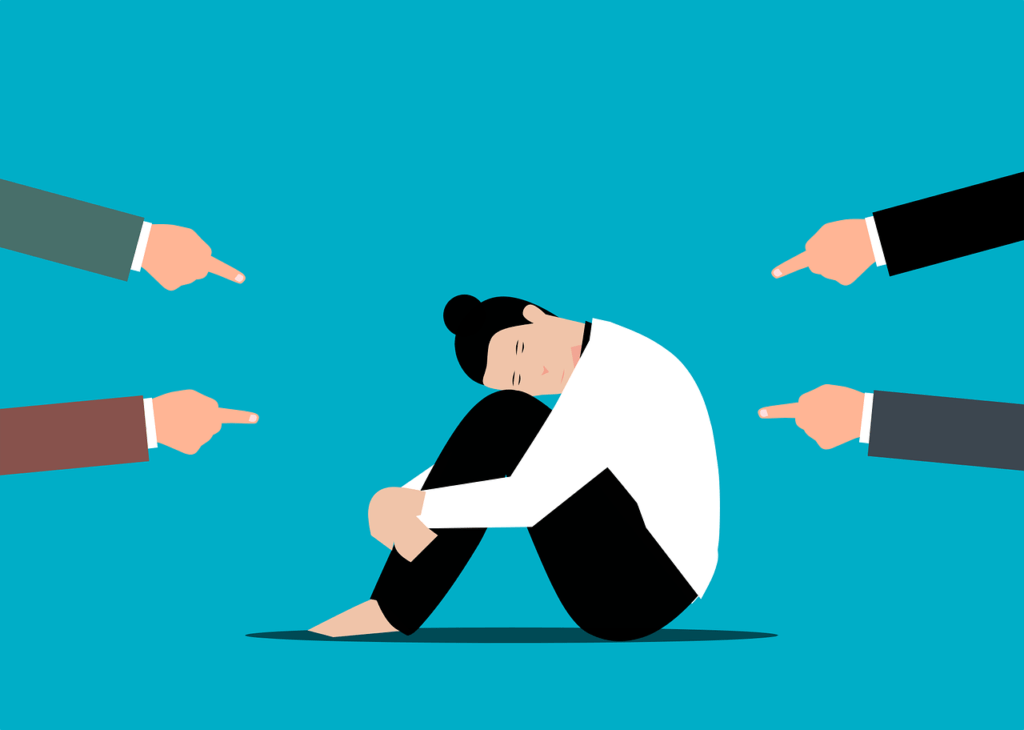 woman in fetal position with 4 fingers pointing at her